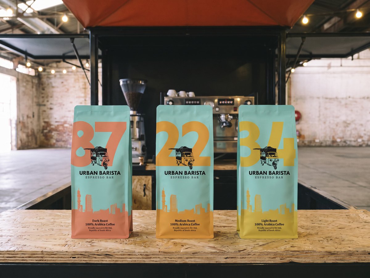 The three Urban Barista bags standing on the counter of the espresso cart, the machine and grinder behind them.